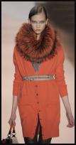  Matthew Williamson fashion design. Wonderful use of Burnt Sienna in a luxurious boyfriend cardigan accessorized with a fur cowl and skinny belts.