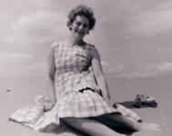 Picture of a woman on the beach wearing a 1950's style dress. Costume history and fashion history 1950s.