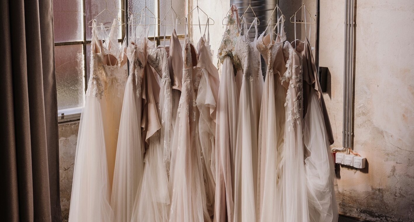 A rack of wedding dresses in soft ivory and blush tones displayed in a bridal studio