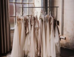 A rack of wedding dresses in soft ivory and blush tones displayed in a bridal studio