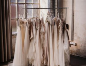 A rack of wedding dresses in soft ivory and blush tones displayed in a bridal studio