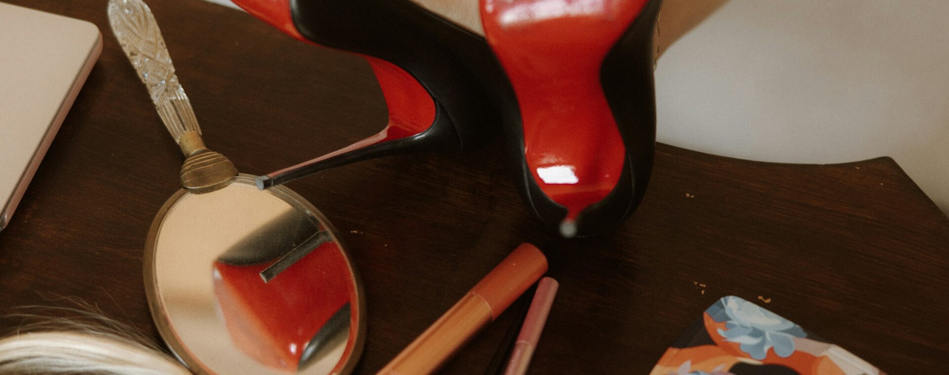 Black high heels with contrasting red soles displayed on a dressing table