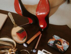 Black high heels with contrasting red soles displayed on a dressing table