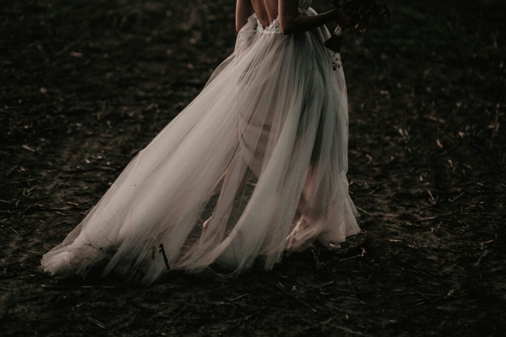 Close-up of a bride walking in a flowing tulle wedding dress with a long trailing skirt