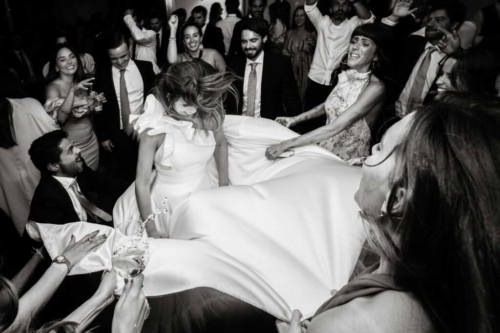 A bride dancing at a wedding reception while guests gather around her flowing gown