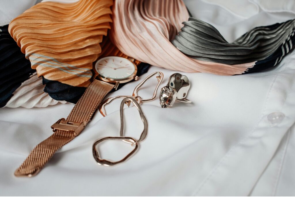 Brown knit sweater with leather accessories in a flat lay.