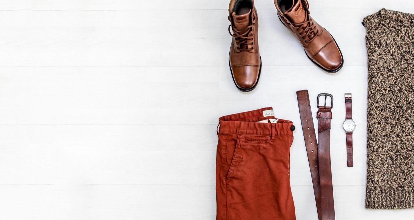 Brown leather shoes with rust-colored trousers in a flat lay.