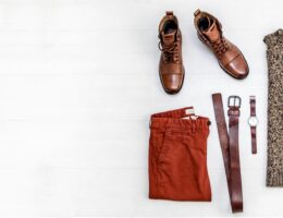 Brown leather shoes with rust-colored trousers in a flat lay.