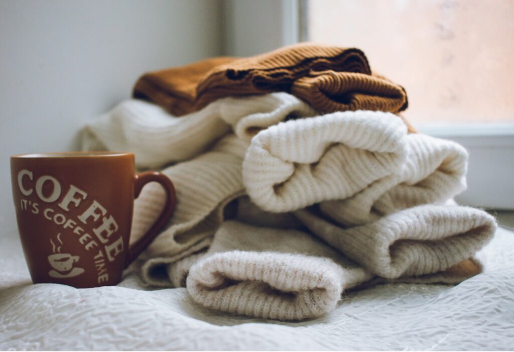 Folded neutral loungewear stacked on a soft blanket.