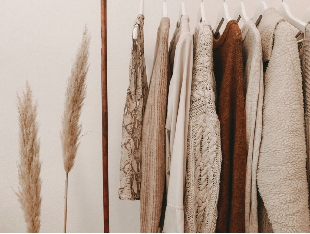 Neutral clothing hanging neatly on a clothing rack.