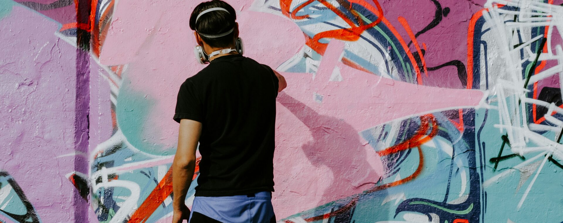 Graffiti artist painting a colourful abstract mural on an urban wall