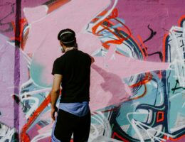 Graffiti artist painting a colourful abstract mural on an urban wall