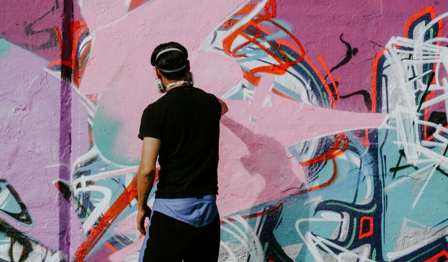 Graffiti artist painting a colourful abstract mural on an urban wall