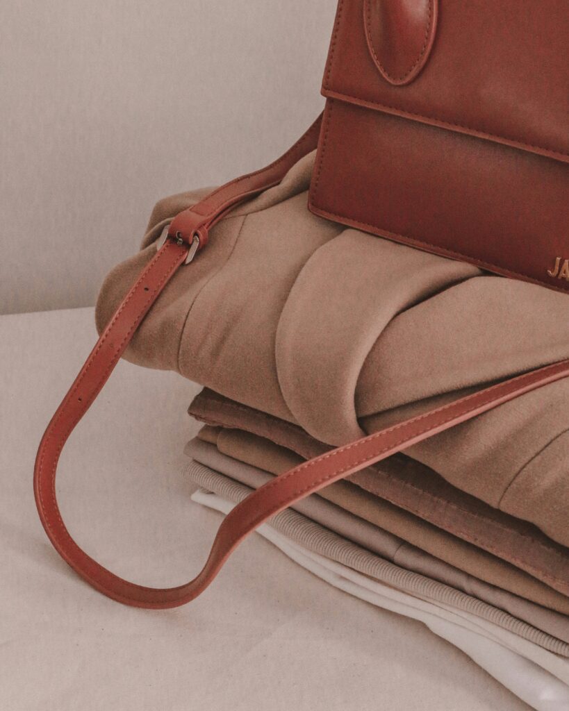 Folded neutral clothing with a red brown handbag as a statement accessory