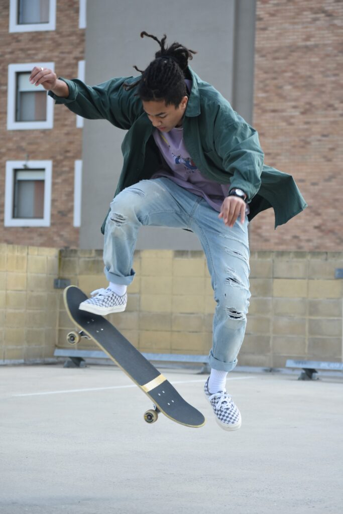 Skateboarder performing a trick in loose jeans, trainers and a casual jacket