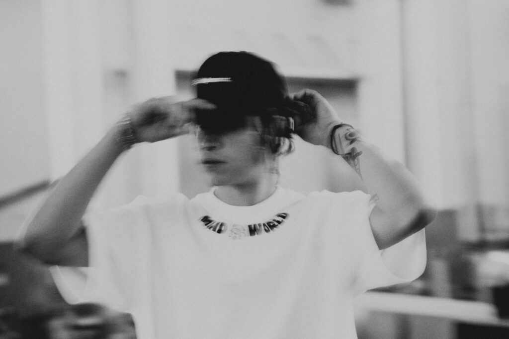 Black-and-white motion portrait of a person wearing an oversized T-shirt and cap