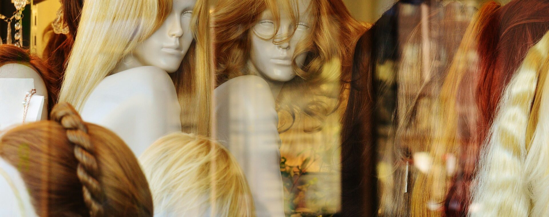 Assorted wigs in blonde, brunette, black, and red displayed on mannequin heads