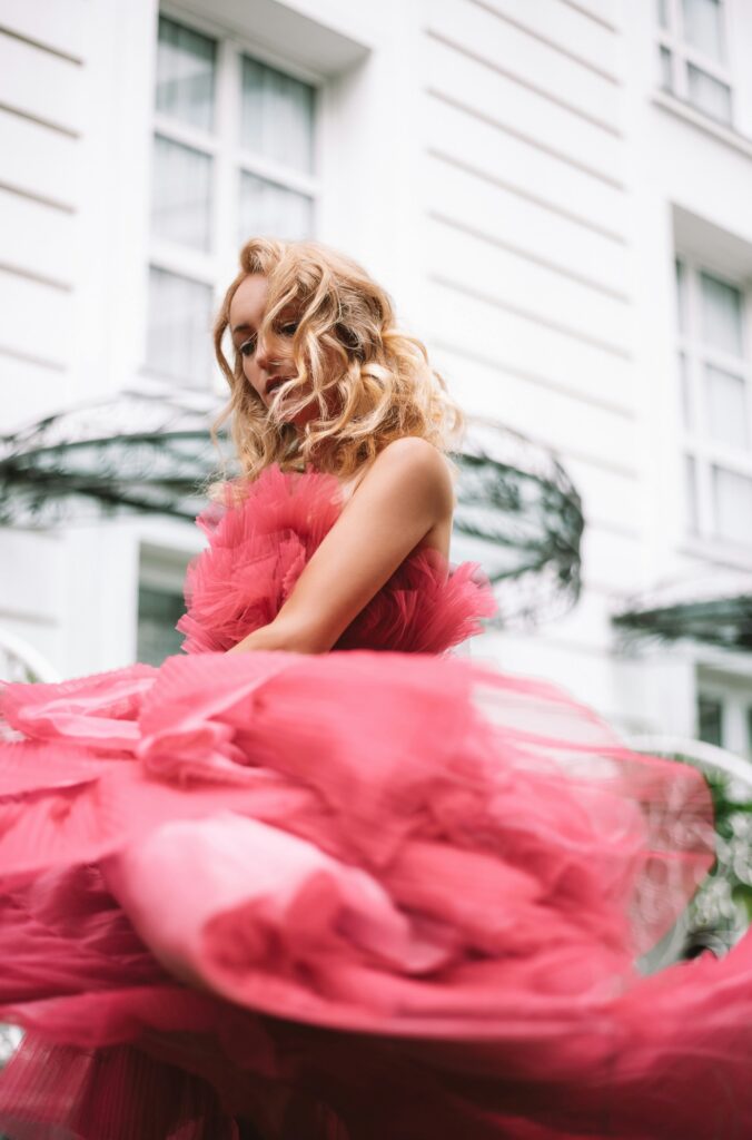 Woman wearing a voluminous bright pink layered tulle gown with a dramatic flowing skirt